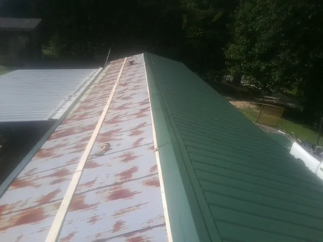 Old rusted panels beside newly installed green metal roofing — Wind Damage Roof Repair by Roofing Brothers in Belleville