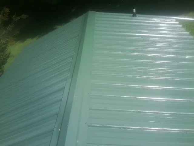 New green metal panels meeting at the ridge of a roof — Flat Roof Repair work by our crew in Belleville