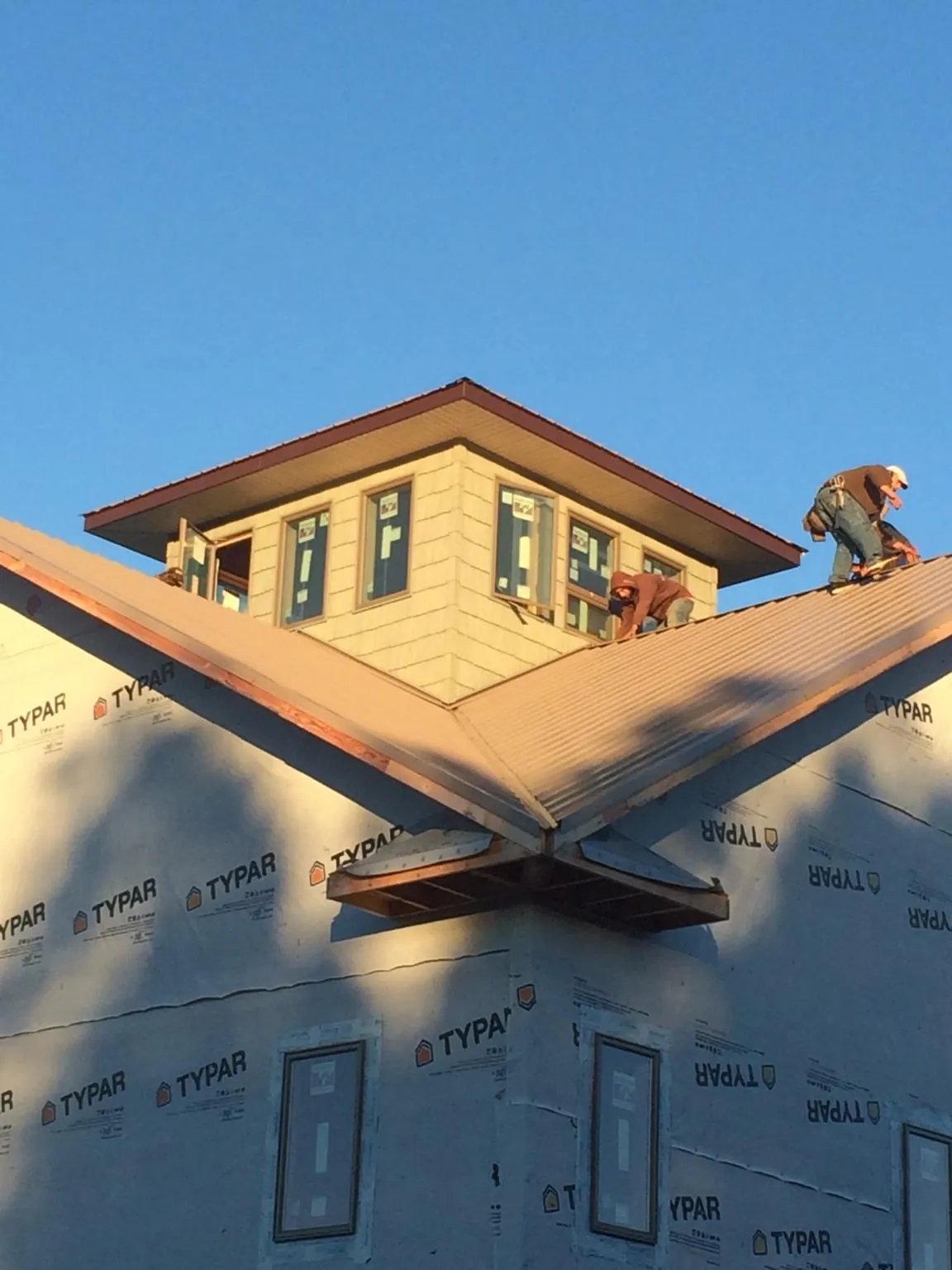 Roofers working around a rooftop cupola on a new metal roof at sunset — Roof Waterproofing in Belleville by Roofing Brothers